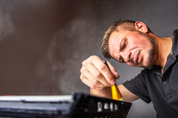 A man works intently on a board, using a brush to clean it. He carefully inspects the parts while...