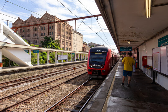 Trem chegando na Esta&ccedil;&atilde;o Juventus Mooca - S&Atilde;O PAULO, SP, BRAZIL - JUNE 23, 2024: Train arriving at Juventus Mooca Station on a sunny Sunday, with the old Antarctica factory building on the left.