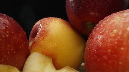 Macrography, slices of fresh apple are arranged on a cutting board against a striking black background. Each close-up shot captures the crisp texture and vibrant colors of the apples. Comestible.