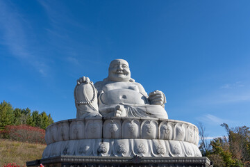 Fototapeta premium Peterborough, Ontario, Canada - October 12, 2024: Maitreya Buddha (Happy Buddha) statue in Wutai Shan Buddhist Garden. Peterborough, Ontario, Canada. 