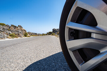 Car wheel on rocky road with clear blue sky in sunshine wide angle lens