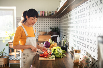 Asian woman chopping vegetables in kitchen for healthy meal prep