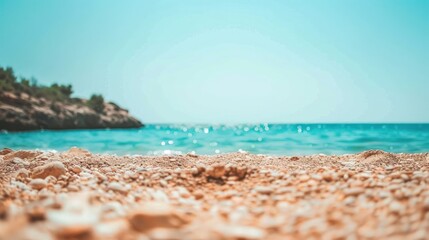 Fototapeta premium Close-up View of Pebbles on a Sandy Beach with a Blurred Ocean and Sky in the Background