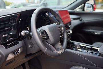 Closeup of a modern car steering wheel with control buttons for technology and convenience