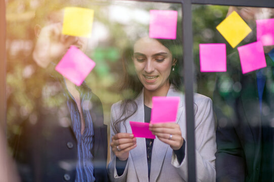 Business people meeting in office, analysis, computational, reasoning, brainstorming, finding business development opportunities, use post it notes to share idea, Sticky note on glass wall.