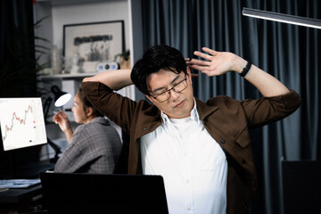Sales manager working on desk with stretching body with arm ache at over late night time at modern...