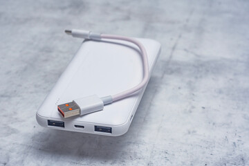 White power bank on a marble table. Portable charger for gadgets.