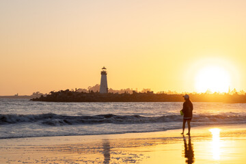 Fototapeta premium The sun was setting, casting a golden glow over the beach. The waves crashed against the shore, their rhythmic sound a soothing balm to the soul.