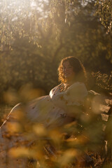 A young brunette plus size woman enjoying sunshine at the evening in a garden outdoors
