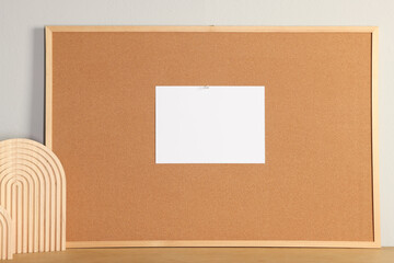 Fototapeta premium Cork board with blank paper note and decorative elements on wooden table near light wall