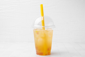 Tasty bubble tea in plastic cup on white tiled table against light background