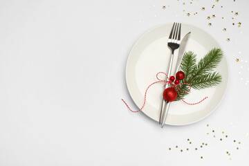 Christmas table setting with plate, cutlery and festive decor on white background, flat lay. Space...