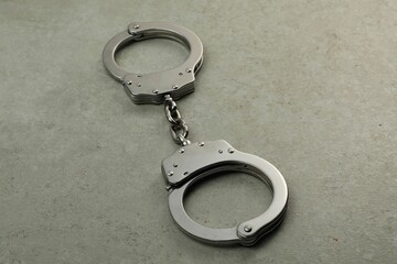 Classic chain handcuffs on grey table, closeup