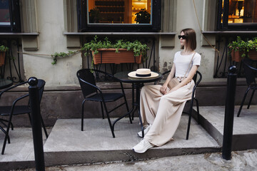 A young girl sits in a street cafe on the street.