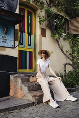 A young girl dressed in wide trousers and a hat walks through the old city.