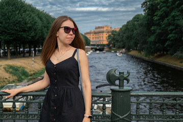 Girl in black dress and glasses stays on the bridge
