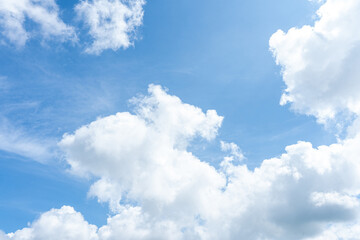 Fluffy white clouds drift across a bright blue sky, casting soft shadows on the Earth