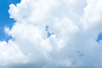 Fluffy white clouds drift across a bright blue sky, casting soft shadows on the Earth