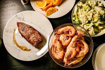 Surf and Turf Dinner with Side Dishes. This vibrant overhead shot captures an elegant surf and turf meal arrangement. 