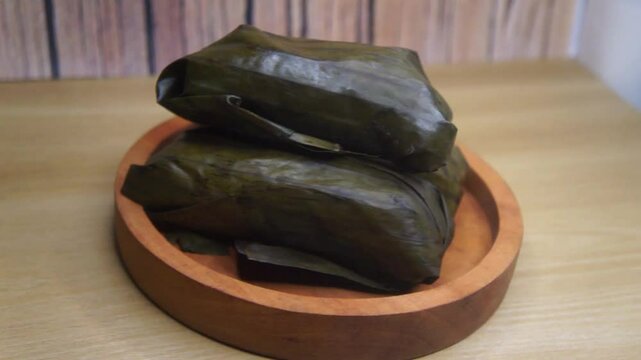 three pieces of lontong filled with oncom on a wooden plate