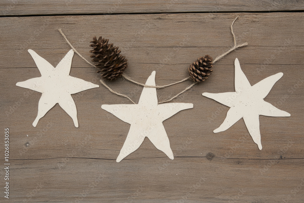 Poster three stars are hanging from a string with pine cones in between them