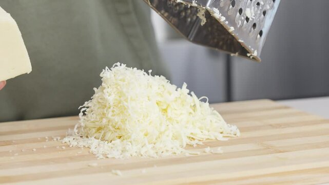 Slow motion of chef grating traditional parmesan cheese with steel grater on the wooden board