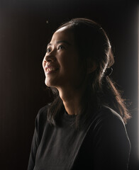 A young woman is smiling beautifully and gracefully in a soft lowlight setting ambiance