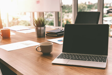 Laptop computer with opened lid on table in meeting room of office workspace. uds