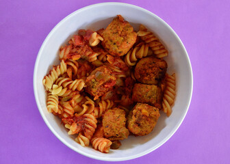 Italian style meatballs with pasta, tomato sauce and cheese in a bowl.