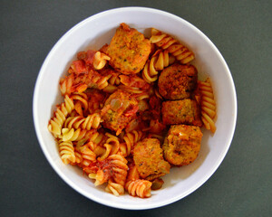 Italian style meatballs with pasta, tomato sauce and cheese in a bowl.