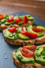 Avocado toast topped with tomato and green onion on a slice of carrot bread