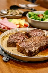 Steak Dinner with Side Dishes. A warm and appetizing spread featuring grilled steaks, seared to perfection, presented on a ceramic plate. 