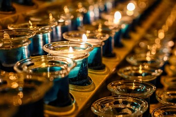 Rows of Glass Candles Illuminated in Warm Light. A captivating display of glowing candles in glass...