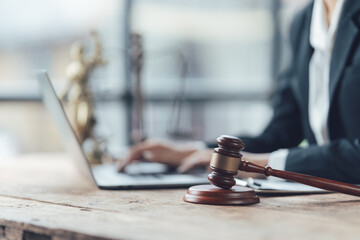 Justice in Progress: A lawyer works diligently on a laptop, with a gavel and Lady Justice statue in the background, symbolizing the pursuit of justice and legal expertise.