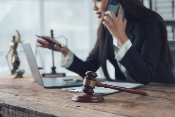 Focused and Determined: A female lawyer works diligently in her office, balancing a phone call, a...