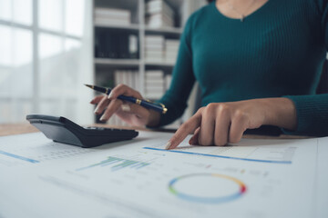 Financial Analyst at Work: Close-up shot of a woman's hands meticulously reviewing financial...