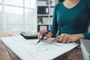 Analyzing the Data:  A close-up shot of a woman's hands meticulously reviewing financial documents,...