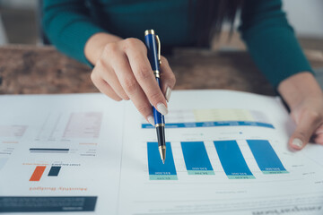 Analyzing the Data: A close-up of a female hand pointing at a bar graph on a spreadsheet, symbolizing data analysis, financial planning, and strategic decision-making.  