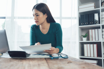 Fototapeta premium Focused Young Professional Woman Reviewing Documents at Desk 