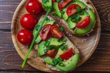 Avocado toast topped with tomato and green onion on a slice of carrot bread
