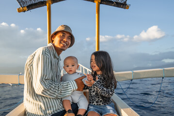 A man along with two children is happily sitting together on a boat while floating in the vast...