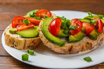 Avocado toast topped with tomato and green onion on a slice of carrot bread