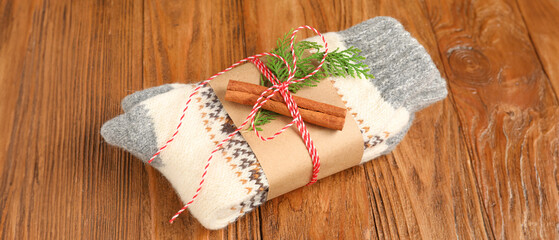 Christmas knitted socks with coniferous branch and cinnamon on wooden background