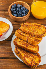 French toast on a plate with blueberries, orange juice, nectarine for breakfast