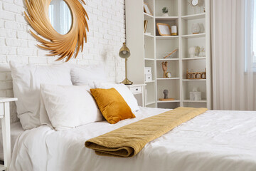 Interior of light bedroom with big bed, mirror and shelf unit