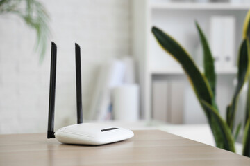 Modern wi-fi router on desk in office, closeup