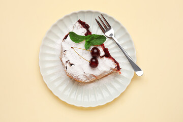 Plate with piece of tasty cherry strudel on pale yellow background