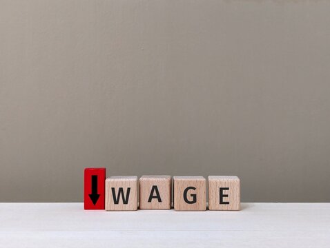 wooden cube with the word Wage and downward arrow. reduction of salary or deduction concept. business finance