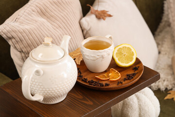Teapot, cup of green tea, lemon and dried cloves on table in room. Closeup