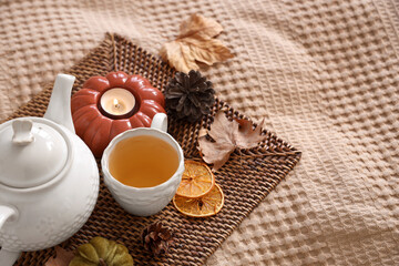 Teapot, cup of green tea and autumn decor on bed in bedroom. Closeup